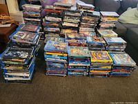 Wide view of dozens of stacked Blu-ray and DVD cases on floor
