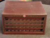 Front view of the antique wooden Star Twist sewing thread display case, showing the closed drawers and gold lettering.