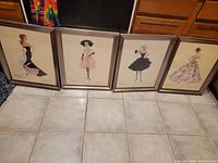 Four framed Barbie fashion sketch prints displayed together on tile floor