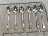 Six coffee spoons arranged on grey cloth insert