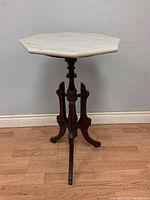 Front view of the antique Victorian walnut parlour table with octagonal white marble top and three-legged wooden base.