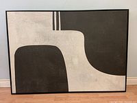 Full view of the framed abstract print with black and white shapes.