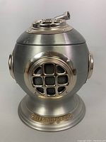 Front view of pewter-tone diver helmet ice bucket with brass plaque marking 'Livorno 1894' on base
