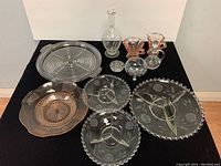 Overview of all glassware items including sectional platters, peach depression glass platter, sugar and creamer sets, cruet, and small dishes.