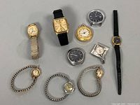Nine vintage watches laid out on a flat surface showing varied styles, dial shapes, and bands including leather, expansion bands, and pendant watches.
