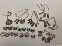 Overview of entire jewelry lot showing 6 pewter necklaces with various pendant shapes, 10 pewter rings arranged in two rows, and 2 pairs of clip-on earrings.