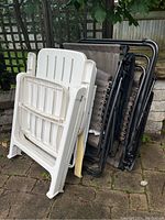 Stacked view of both chairs folded and leaning against a wall outdoors.