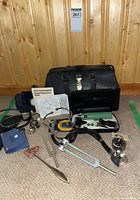 Full lot view showing all items spread on carpet in front of wooden paneled wall including doctor's bag, blood pressure cuff, stethoscope, tuning forks, reflex hammer, and reference charts.