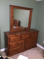 Front view of solid pine dresser with attached mirror, showing wood grain and drawer layout.