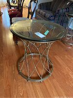 Front view of round glass top table on brass-tone metal lattice base