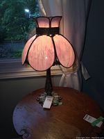 Full lamp lit showing pink stained glass shade shaped in petal-like panels, ideal for vintage decor.