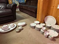 Photo showing the collection of Limoges and additional china dishes grouped on floor including plates, bowls, cups, and serving pieces.
