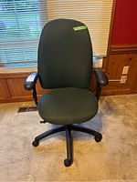 Front view of green fabric office chair showing the high backrest, armrests, and five black caster wheels.