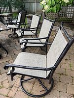 Four chairs on brick patio around glass-top table, view showing overall set