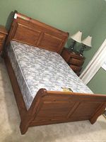 Angle view of queen bed frame with mattress against green wall