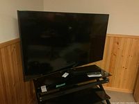 Samsung 54 inch television on stand in a basement room with wood paneling on the wall.