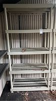 Front view of resin shelving unit showing four slatted shelves and vertical posts.
