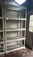 Full view of resin shelving unit in a shed corner with vertical slatted siding and window.