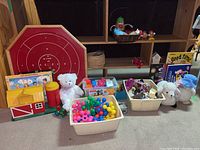 Full view of toys lot including barn, crokinole board, teddy bear, baskets of toys, puzzle, and stuffed sheep.