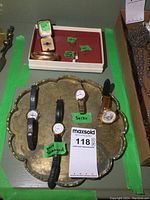 Overview of four watches on brass tray and jewelry box with rings, earrings, bangle