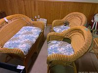 Three-piece wicker seating with love seat and two chairs, cushions in place