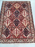 Full view of the Persian Bakhtiar hand knotted wool rug showing the tribal panel design in dark red, navy, ivory with geometric and leaf motifs.