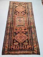 Full view of hand knotted Malayer wool rug with geometric design in earth tones.