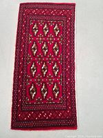 Full view of the rectangular deep red Turkman rug with traditional motifs and geometric borders.