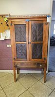 Full front view of the Amish-style pie safe cabinet showing punched tin star-pattern doors and bottom drawer with wooden knobs.