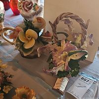 Two Capodimonte floral baskets side by side on table, showing detailed flowers and basket shapes