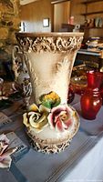 View of Capodimonte vase showing detailed scroll and leaf relief pattern with attached roses on base.