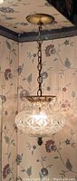Crystal hanging ceiling light fixture suspended by a metal chain with ornate metal canopy, featuring a round cut glass crystal globe shade and antique brass hardware.