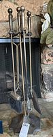 Full view of brass fireplace tool set on stand with five tools: poker, tongs, brush, shovel, and one additional tool.