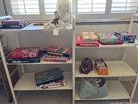 Overall view of children’s games on shelves showing boxed games, a plush rabbit, and a Dolly bag with doll.