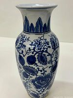 Front view of the ceramic vase showing blue floral and fruit motifs on white surface.