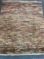 Full view of rectangular carpet showing multicolor linear pattern on concrete floor