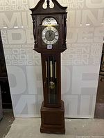 Full front view of the entire clock showing case, dial, weights, and base