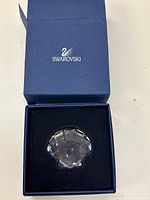 Swarovski branded blue box with foam insert containing a clear crystal seashell figurine.