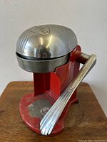 Front and side view of the vintage red and chrome Rival Juice-O-Mat juicer showing overall condition and lever handle.