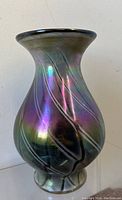 Full front view of iridescent glass vase showing purple and green color shifting and swirled texture pattern.