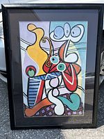 Framed abstract still life art print inspired by Picasso, shown outdoors leaning against a vehicle.