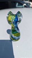 Front view of the mini glass cat figurine showing clear glass with blue, green, and yellow swirls and small round eyes.