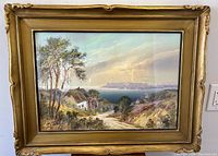 Front view of the framed oil painting showing detailed countryside scene with cottage, trees, and distant landscape under sky.