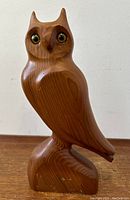 Front view of carved wood owl sculpture showing glass eyes and signed base