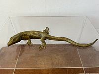 Front angled view of bronze lizard sculpture showing lifelike scales and detailed feet.