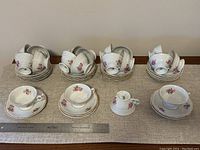Full set of cups and saucers arranged in groups with visible floral patterns and gold rim detailing.