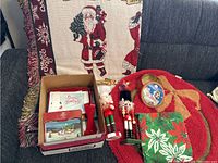 Photo showing the Christmas items including two nutcrackers, festive Christmas cards, Santa Claus tablecloth, Mickey Mouse tin, throw blanket, angel ornament and hooks.