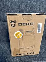 Photo of DEKO water pump in original cardboard packaging showing logo and product illustration.