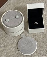 Hillberg & Berk white sparkle ball earrings in branded round storage case, with Pandora ring in white box, and a small grey pouch.