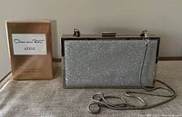 Photo showing both perfume box and silver glitter clutch purse with detachable strap.